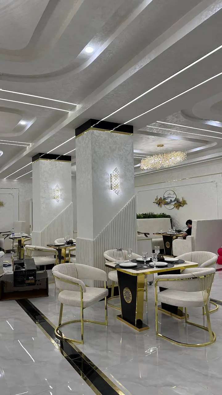 TRINITY restoranining oq va oltin rangdagi ichki zali